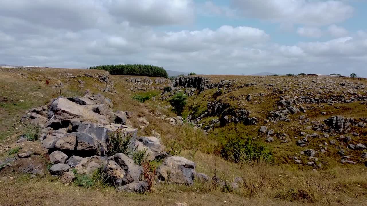Visit a unique area in Peru featuring breathtaking rock formations and rolling grassy fields under a bright sky. Discover the beauty of nature in this serene environment