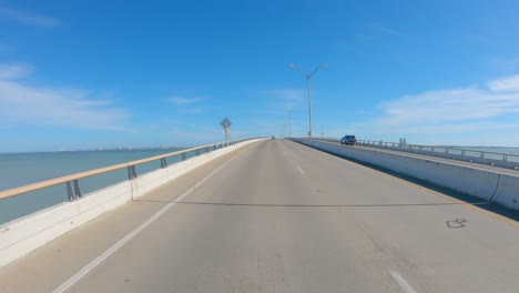 pov thru rear window while driving over queen isabella causeway over laguna madre at south padre island, texas on a sunny afternoon
