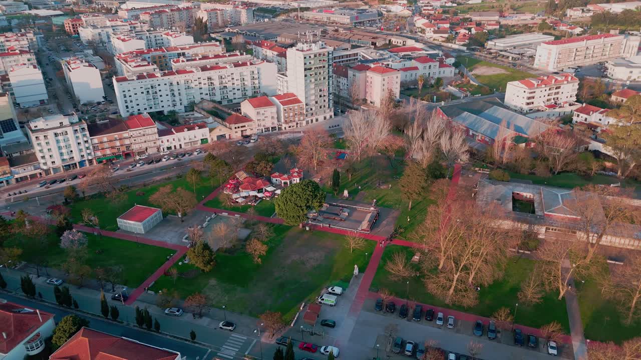 Záběr z dronu stoupající a vzdalující se nad Parque do 25 Abril v Rio Maior v Portugalsku, ukazující lidi, město v pozadí a přírodní park Serras de Aire e Candeeiros