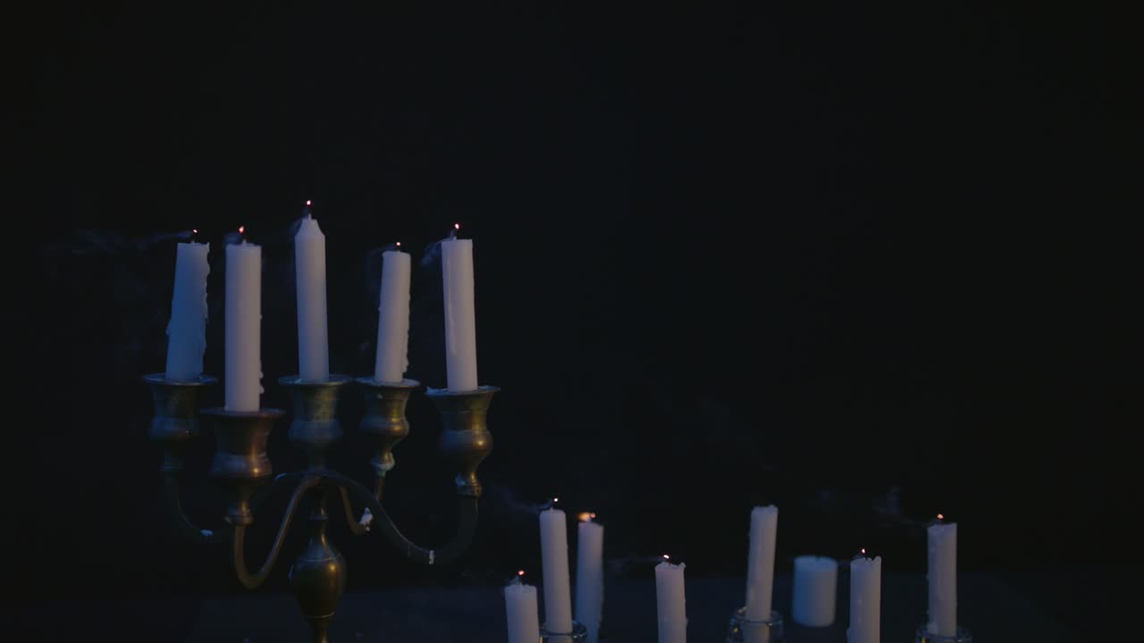 Un gruppo di candele bianche, alcune su un candelabro, accese e poi spente dal vento.