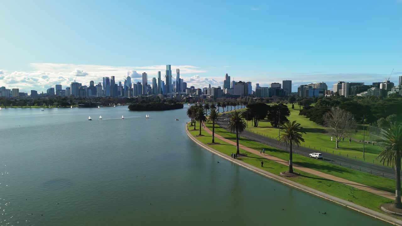 Cinematic flight over Albert Park Lake with Melbourne city skyline in the background
