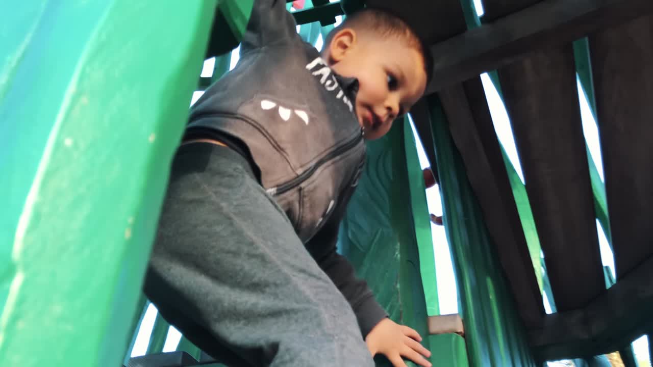 Adorable toddler playing in the wooden house in the park. Low angle