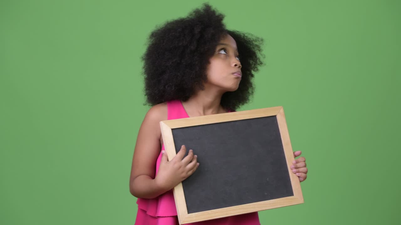Young cute African girl with Afro hair holding blackboard