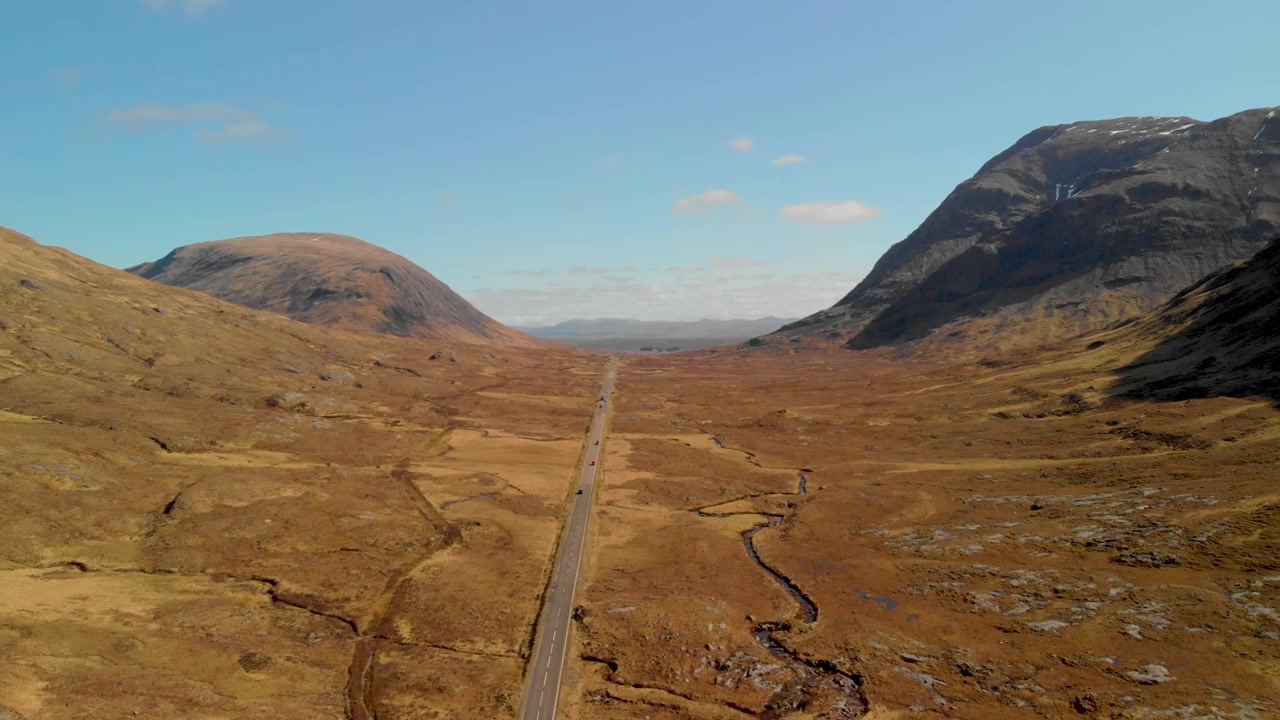 Coches circulan por la A82 a través del valle de Glencoe, flanqueado por imponentes montañas.