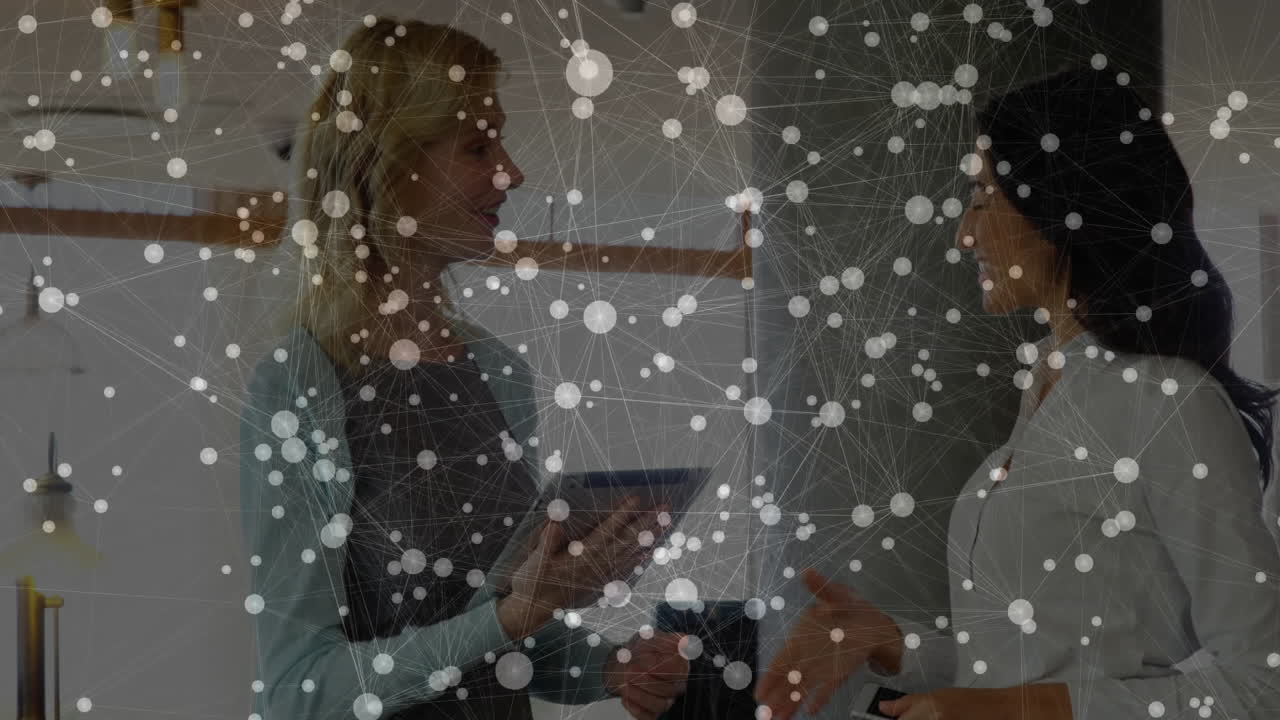 Office colleagues holding tablet and phone discussing business tech with network nodes hovering