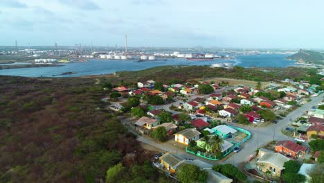 drone rise above neighborhood on hillside to reveal oil refinery industrial port on water