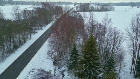 Toma-Aérea-De-Un-Dron-De-Una-Escena-Nevada-De-Invierno-En-Una-Carretera-Rural-Vacía