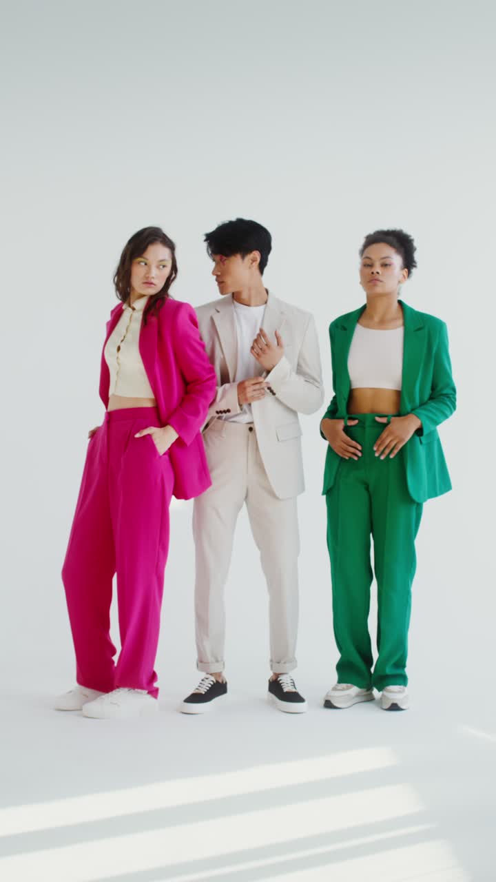 Three people posing in brightly colored suits