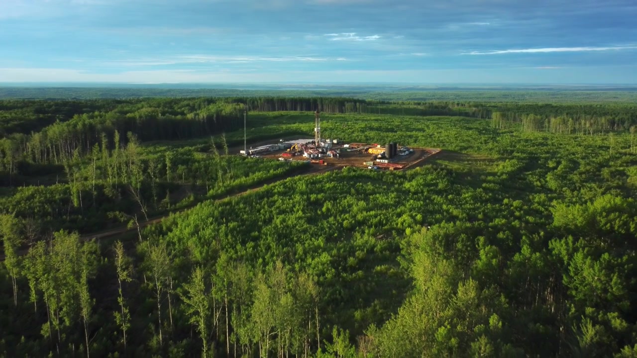 Cinematic Aerial View of a Drilling Rig in Green Fields of Central Alberta, Canada