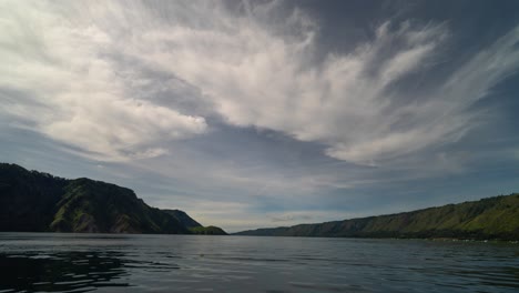 vast lake surrounded by lush green mountains under a dramatic sky