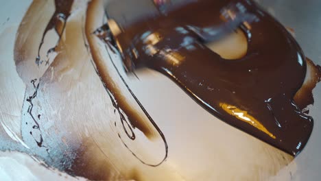 woman mixes chocolate glaze using metal pastry scraper