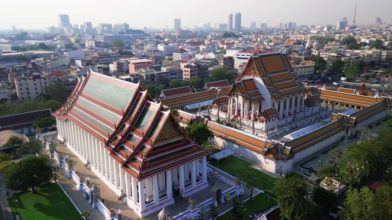 Aerial medium approach to Wat Suthat in Bangkok, Thailand, grand temple complex and surrounding urban environment