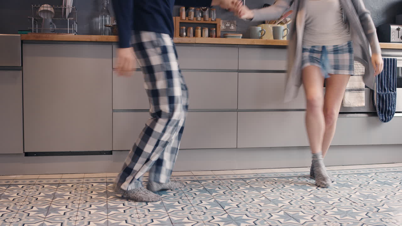 reconocible feliz pareja joven recién casada bailando escuchando música en la cocina con pijama por la mañana en casa enamorada