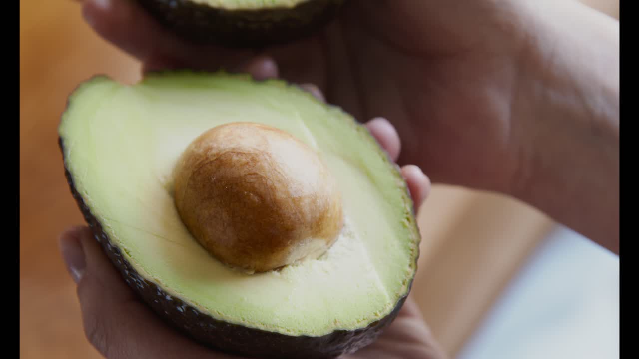 손에 절단 된 아보카도 절반의 클로즈업