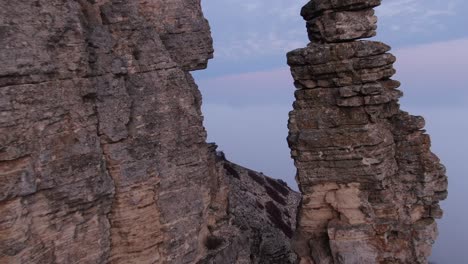 aerial view. flying between rocks in which horizontal layers of rock are visible.