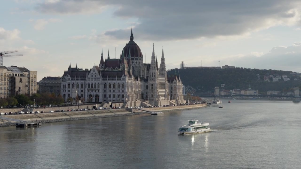 Vista autentica ripresa a mano del Parlamento di Budapest e del fiume Danubio, con un battello fluviale che passa davanti