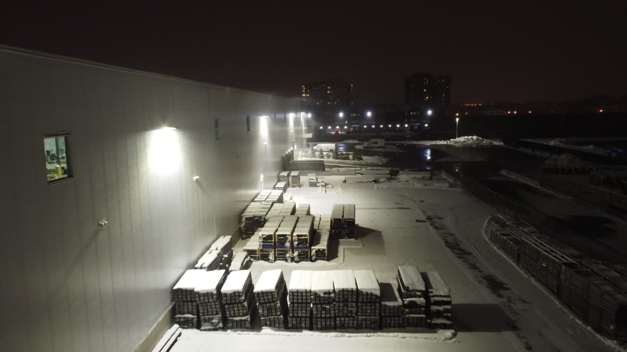 추운 겨울 저녁에 현대식 물류 센터 옆에서 눈으로 뒤덮인 밖에 남겨진 물건 위로 공중 비행