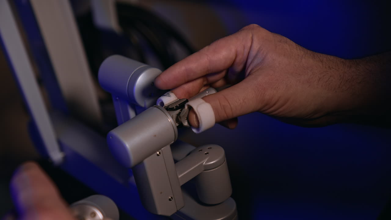 Male hand moving the sensitive rotating handle of a robotic equipment in surgery room. Surgical robot operating by human. Close up.