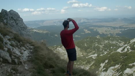 Man-holding-a-snowball-on-his-head-and-then-throwing-it-from-a-mountain-top,-slow-motion