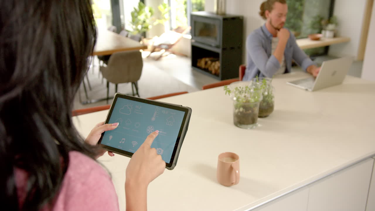 una joven caucásica está usando una aplicación para el hogar inteligente en una tableta en casa