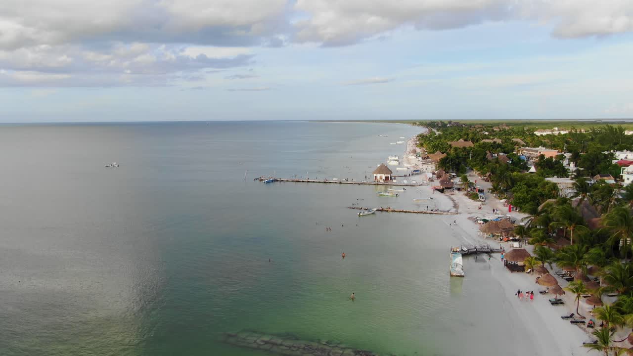Góc nhìn từ trên cao, cảnh quay di chuyển, quang cảnh tuyệt đẹp của bãi biển Isla Holbox ở Mexico, mọi người đang bơi lội quanh bãi biển vào một ngày nắng rực rỡ với bầu trời xanh trong vắt ở hậu cảnh