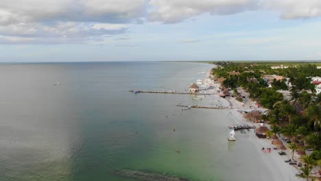 vista aérea en movimiento, vista panorámica de la playa de isla holbox en méxico, gente nadando alrededor de la playa en un día soleado, cielo azul claro en el fondo