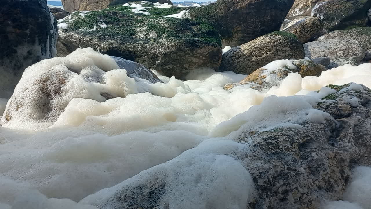 Sea foam over rocks on the beach