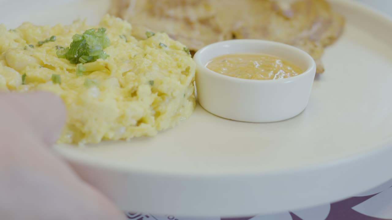 Close-up of a waiter delivering a delicious plate of roast meat accompanied by traditional mote pillo prepared with mote, egg and scallion and a portion of ají