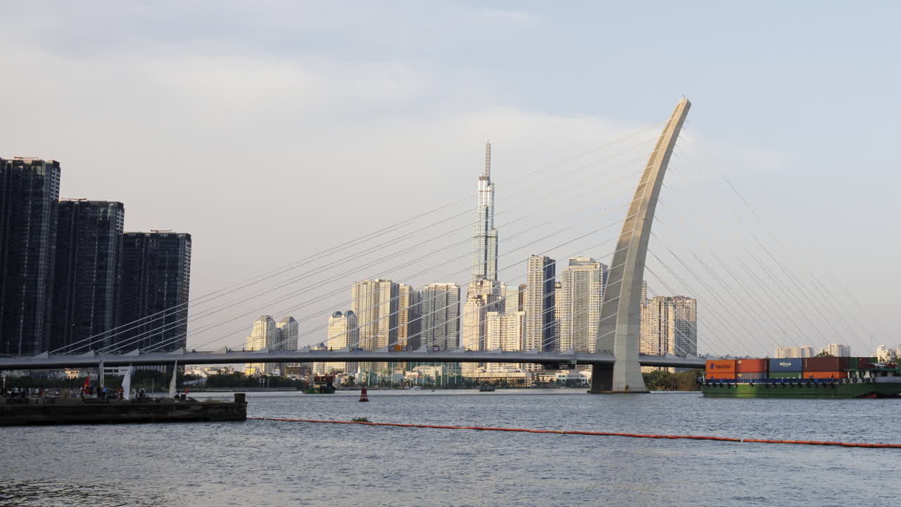 A static timelapse focusing on Saigon River’s bridge and moving cargo vessels, capturing steady river traffic and urban activity without camera movement