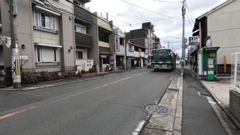 green bus travels down a suburban street