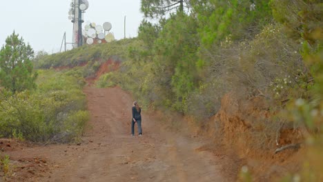 wide shot of girl from behind hiking on trail path in tenerife tv tower on peak