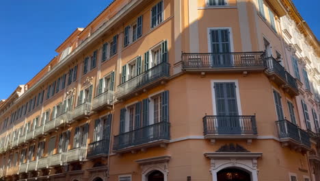 ornate european building with peach facade, blue shutters, and balconies