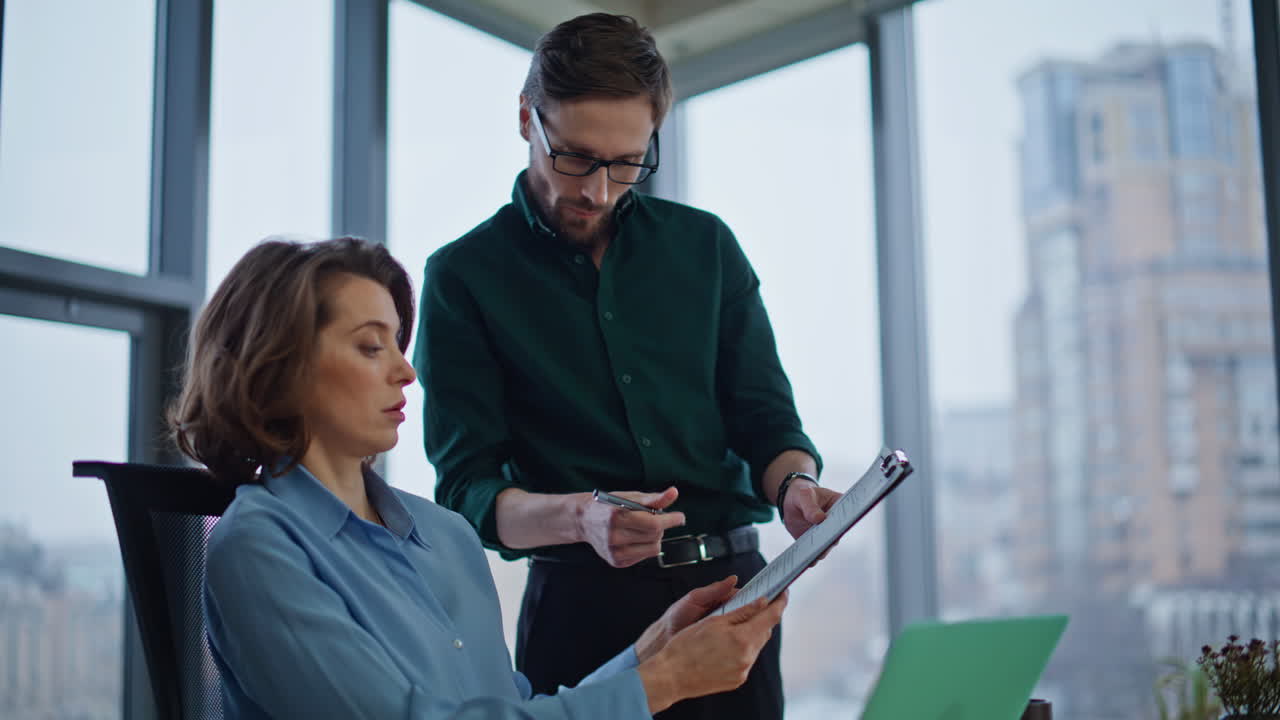 Man secretary bringing report to woman boss for signing at workplace closeup