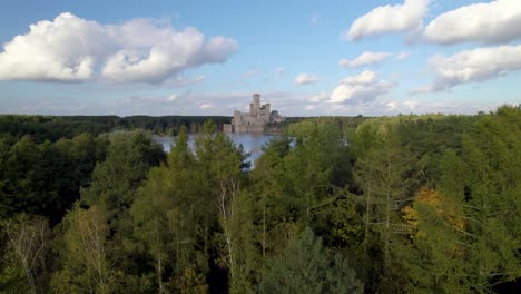 Luftaufnahme-Des-Wunderschönen-Schlosses-Stobnica,-Polen---Eine-Große-Touristenattraktion,-Erbaut-Auf-Einer-Künstlichen-Insel-Auf-Einem-See-Inmitten-Eines-Unbewohnten-Waldes