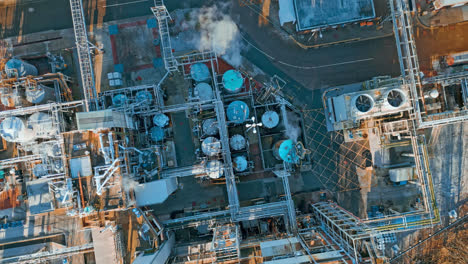 aerial footage moving towards a large industrial chemical plant, showing pipelines, metal structures, cooling towers and chemical storage