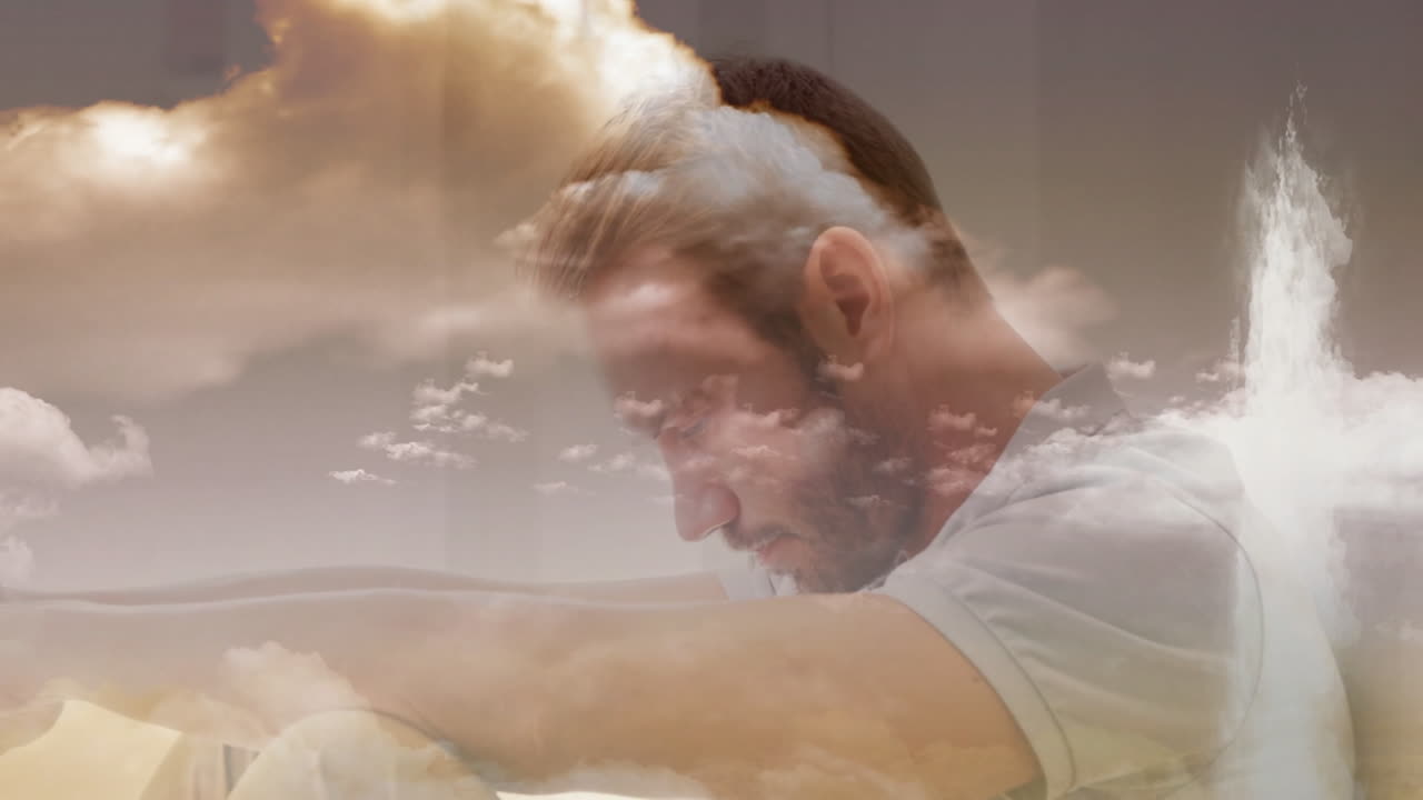 Sitting with head down, man overlaid with serene clouds and sky animation