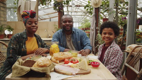 portrait of happy african american family at dinner in greenhouse