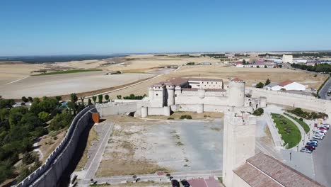 aerial-approaching-medieval-castle,-main-square-church,walls-and-garden