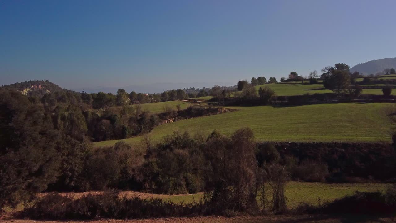Colline ondulate e vegetazione lussureggiante nella regione di Marganell, Barcellona, Spagna, sotto un cielo azzurro e limpido