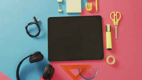 video of composition of school items and tablet with copy space on blue and pink surface