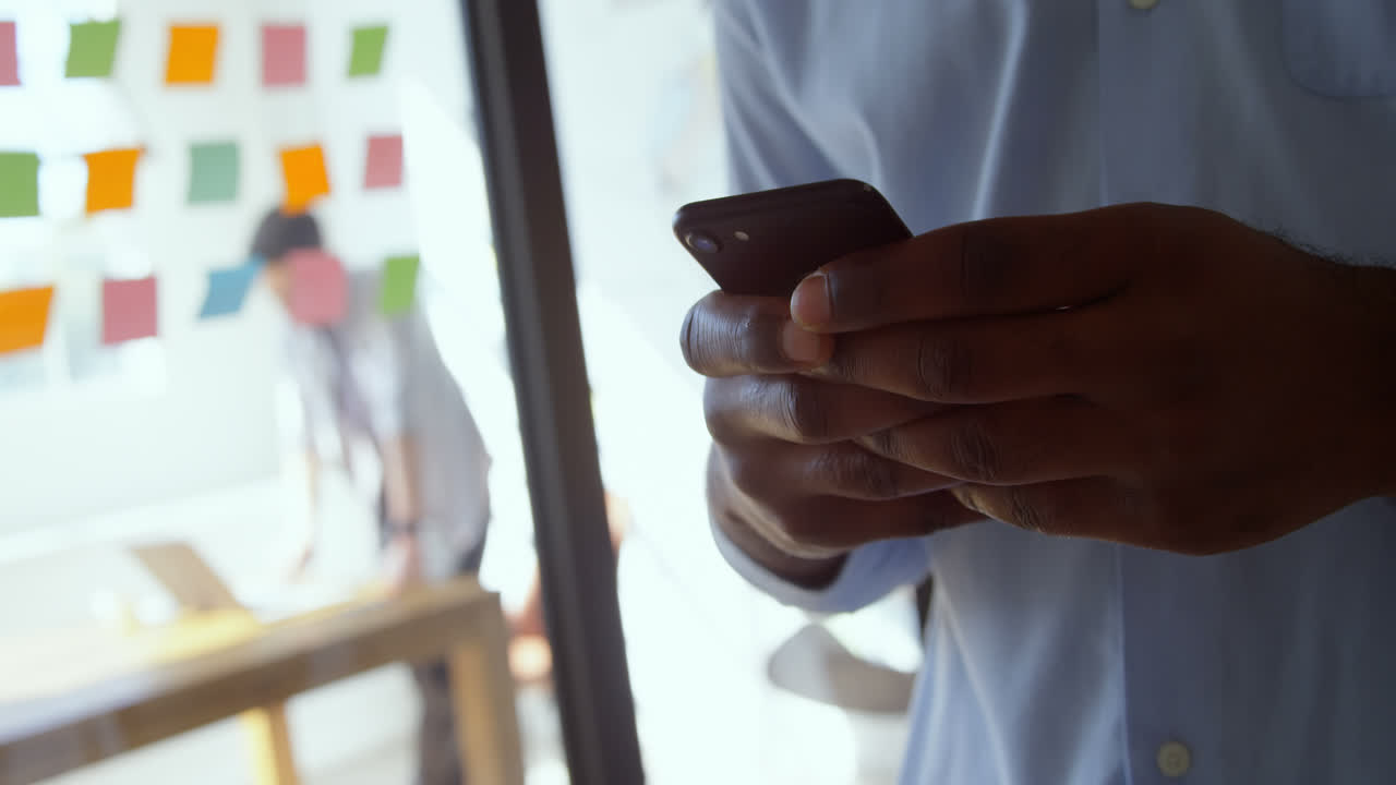 Close-up of young black businessman working on smartphone in a modern office 4k