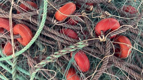 Fishing-nets-and-buoys-tackle,-stock-pile-of-net-packed-on-large-stack,-daytime-video-capture,-maritime-and-fishing-concept