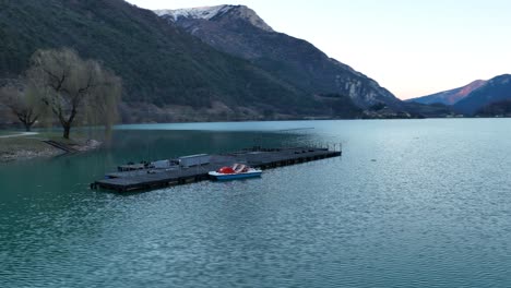Aerial-Rotating-Drone-shot-of-boat's-platform-on-Ledro's-Lake---Not-Graded
