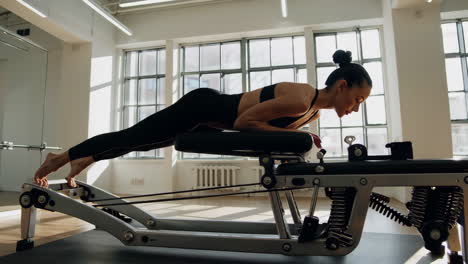 woman performing exercises on a pilates reformer machine