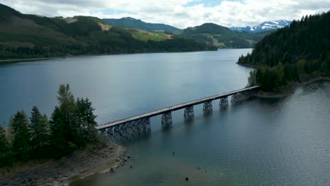 drone-shot-over-campbell-river-upper-campbell-lake-trestle-bridge-near-Strathcona-regional-park-in-Vancouver-Island-on-a-cloudy-day