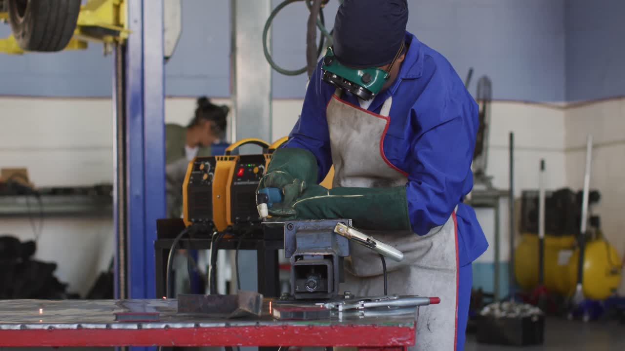 Video of african american female car mechanic using grinder, preparing car parts