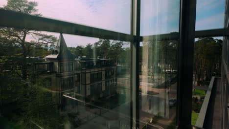 View-from-a-descending-elevator-showcasing-Jurmala's-forest-houses-and-natural-scenery-through-reflective-glass,-capturing-the-serene-blend-of-architecture-and-nature-in-Latvia