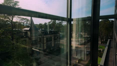 vista desde un ascensor descendente que muestra las casas forestales de jurmala y el paisaje natural a través de vidrio reflectante, capturando la serena mezcla de arquitectura y naturaleza en letonia