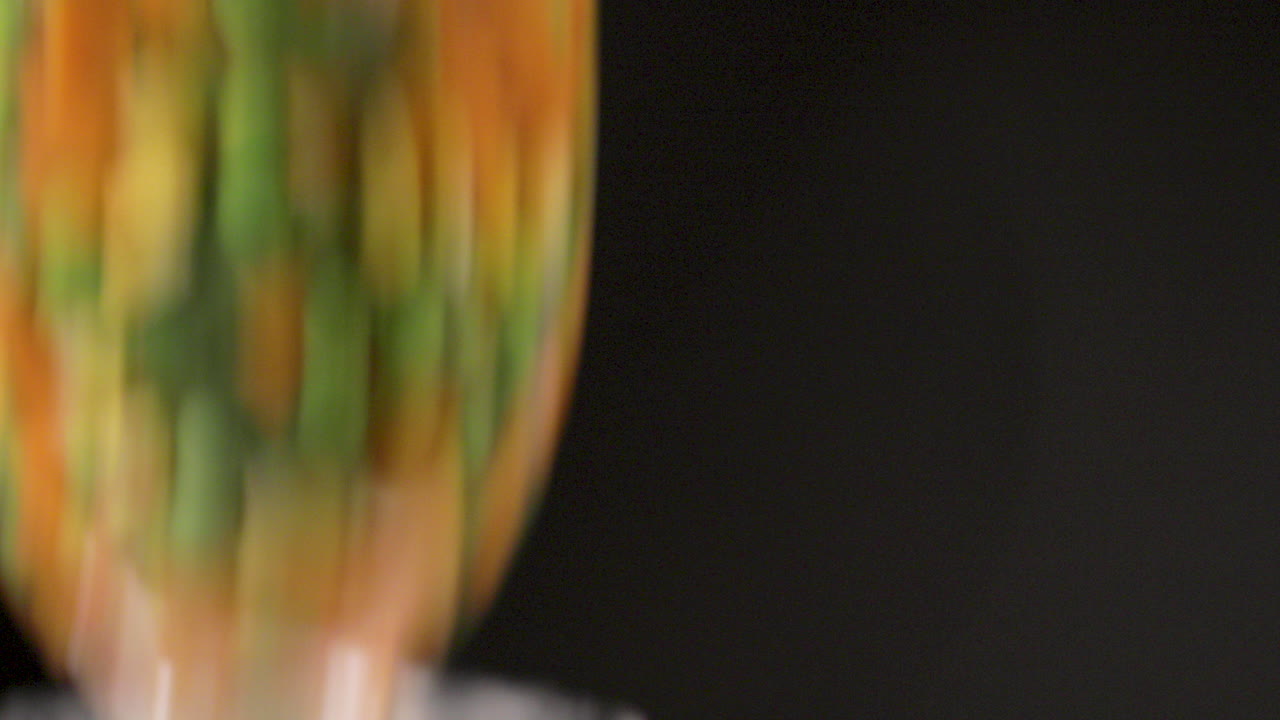 mezcla de verduras frescas caídas en el agua dentro de un vaso con combinación colorida con un fondo negro y filmado en 4k