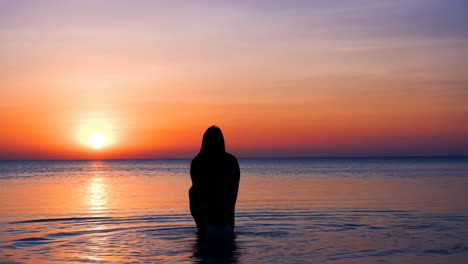 Woman's silhouette against a vibrant ocean sunset